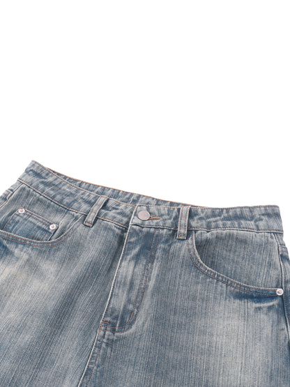 Vintage wash distressed denim jeans by ODMPOD, showing a close-up of the faded, torn fabric and classic jean details.